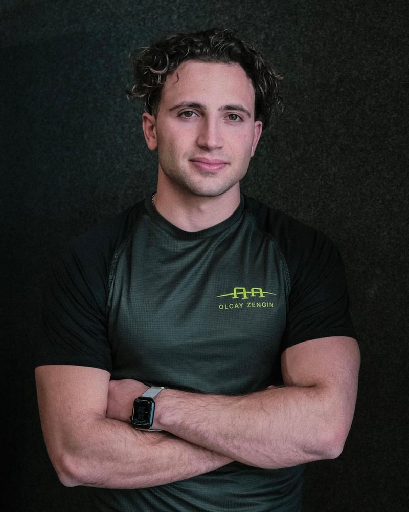 Olcay Zengin, Calisthenics-Coach, mit verschränkten Armen vor dunkler Wand